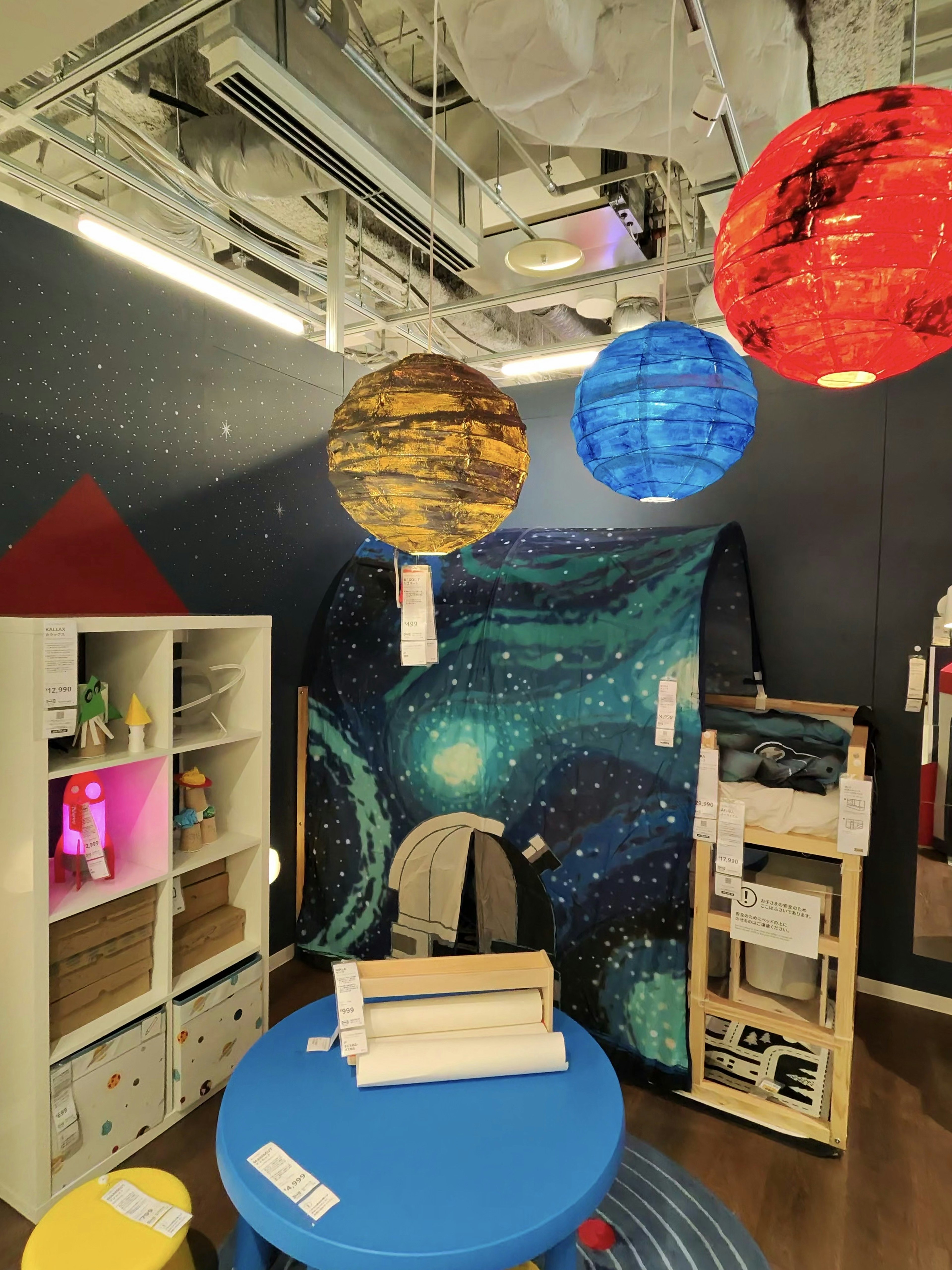 IKEAのディスプレイ。天井から色とりどりのペーパーランタンが吊るされ、子供向けの家具や装飾品が配置されいる