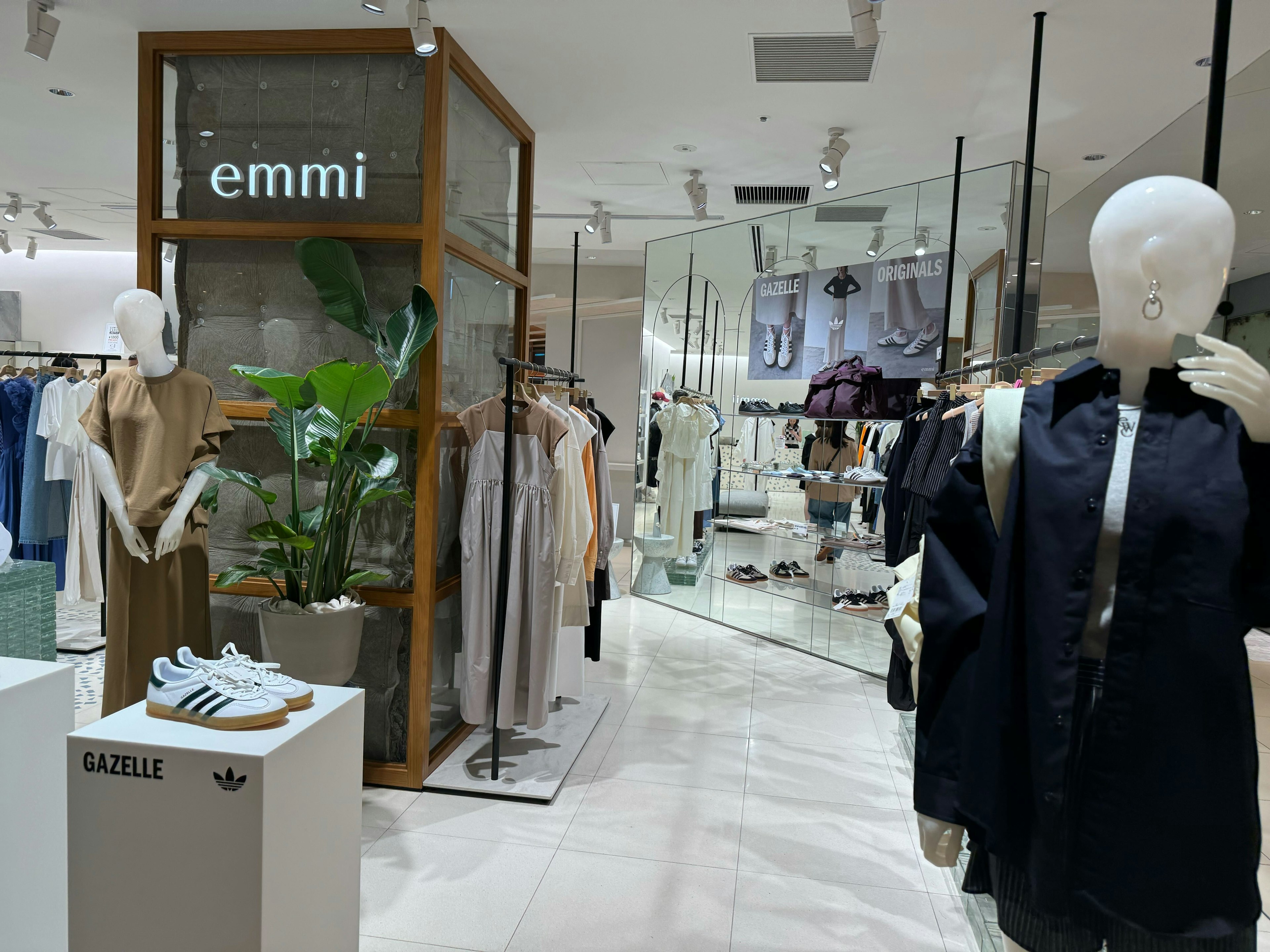 「emmi」ロゴのあるショップ内、モダンな服とスニーカーが並ぶ洗練されたディスプレイ。