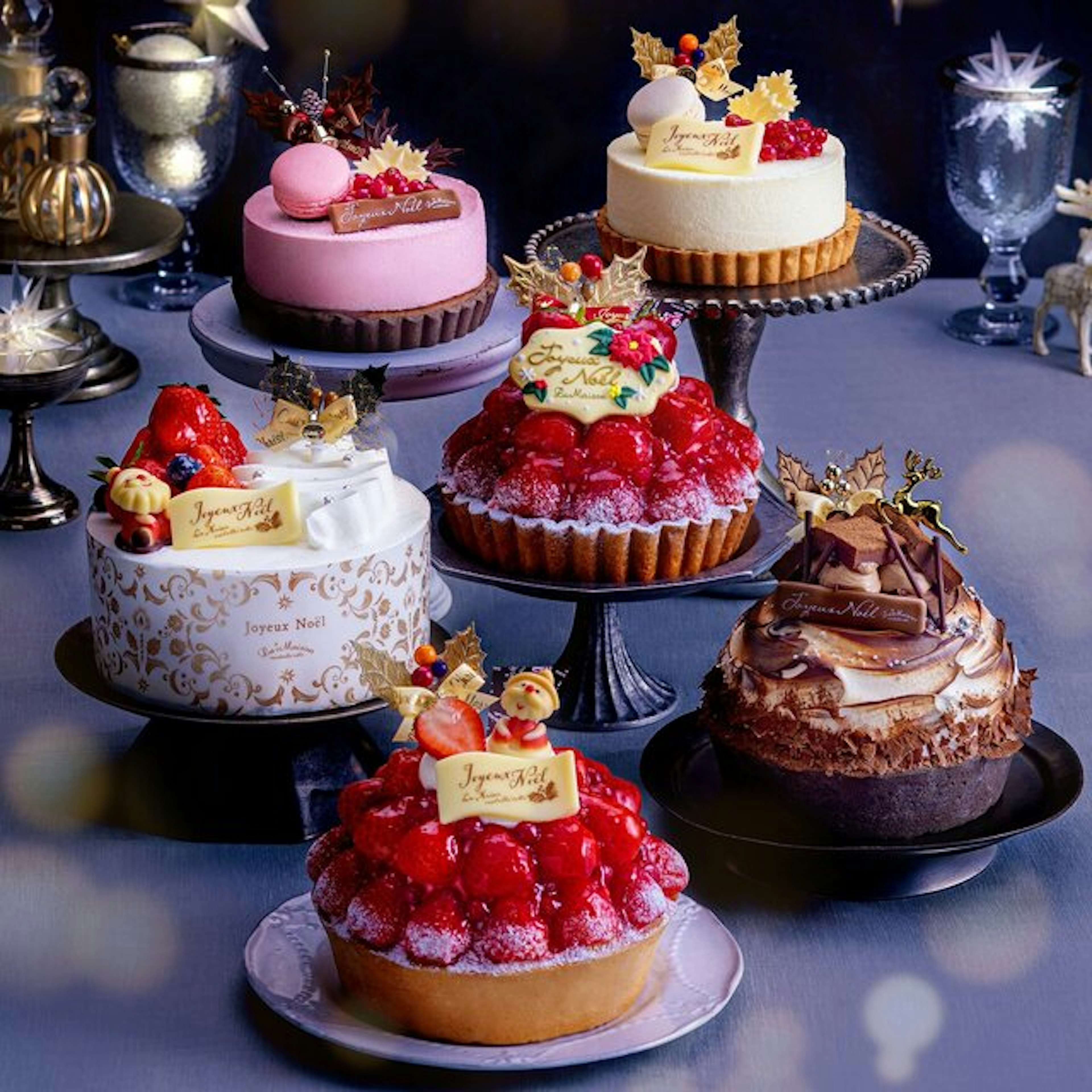 クリスマス仕様の華やかなデコレーションケーキがテーブルに並んでいる。苺やチョコレートがふんだんに使用された豪華なラインナップが特徴。