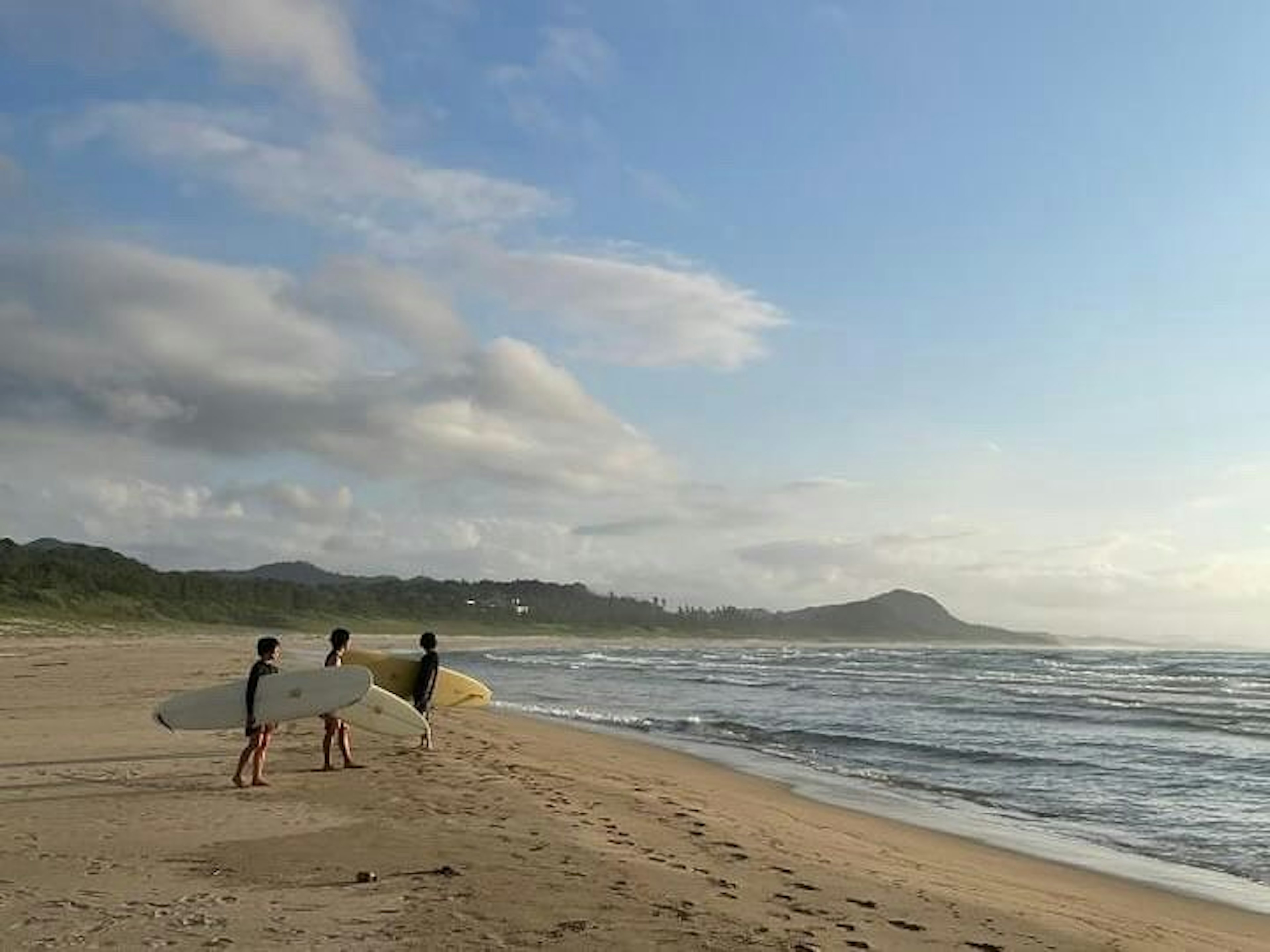 青空の下、海でサーフィンを楽しんでいる人たち