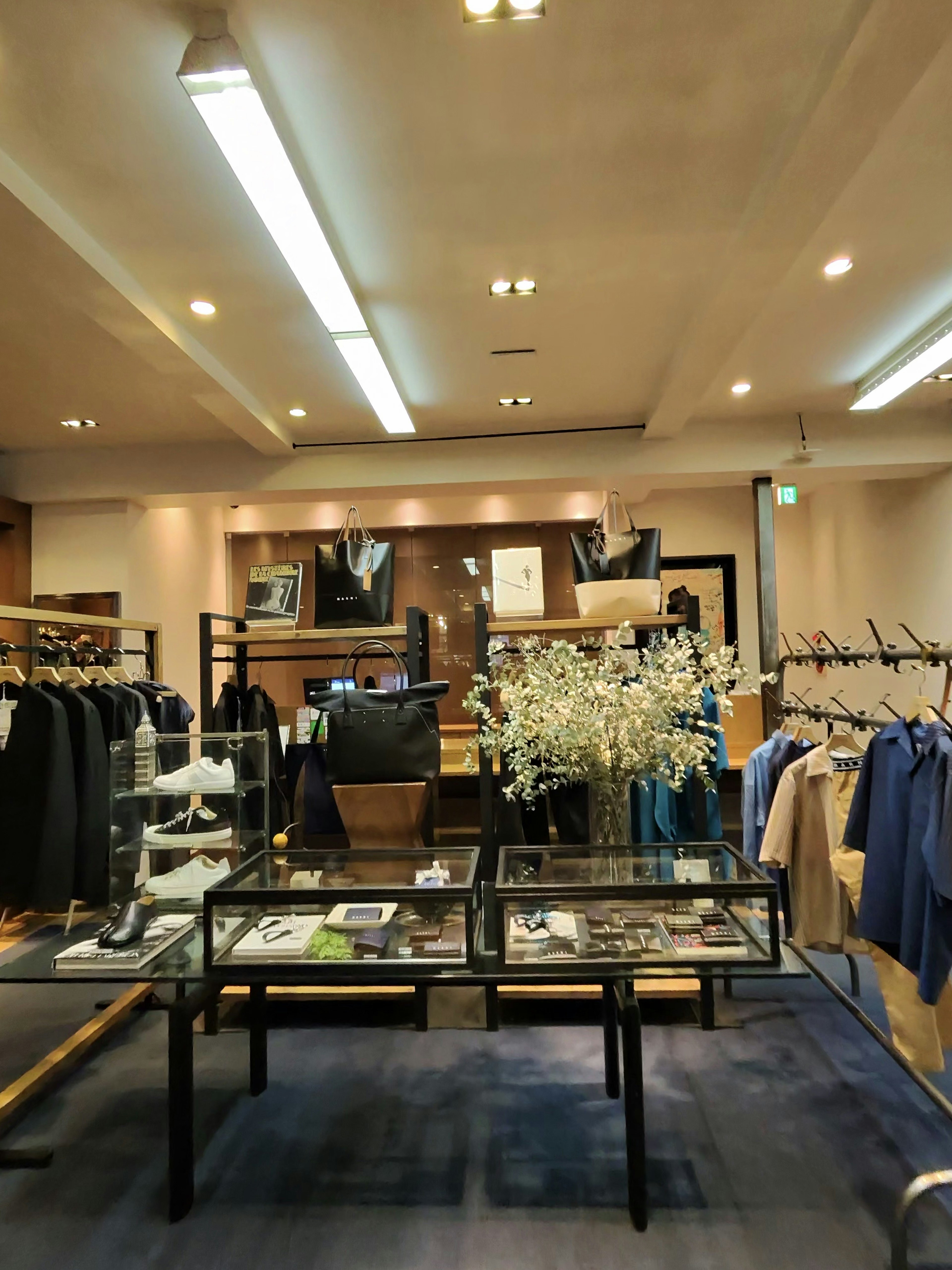 EDIFICEの店内。店内奥には黒とネイビーのジャケットが掛かったラックと、洗練されたデザインのバッグが陳列されている