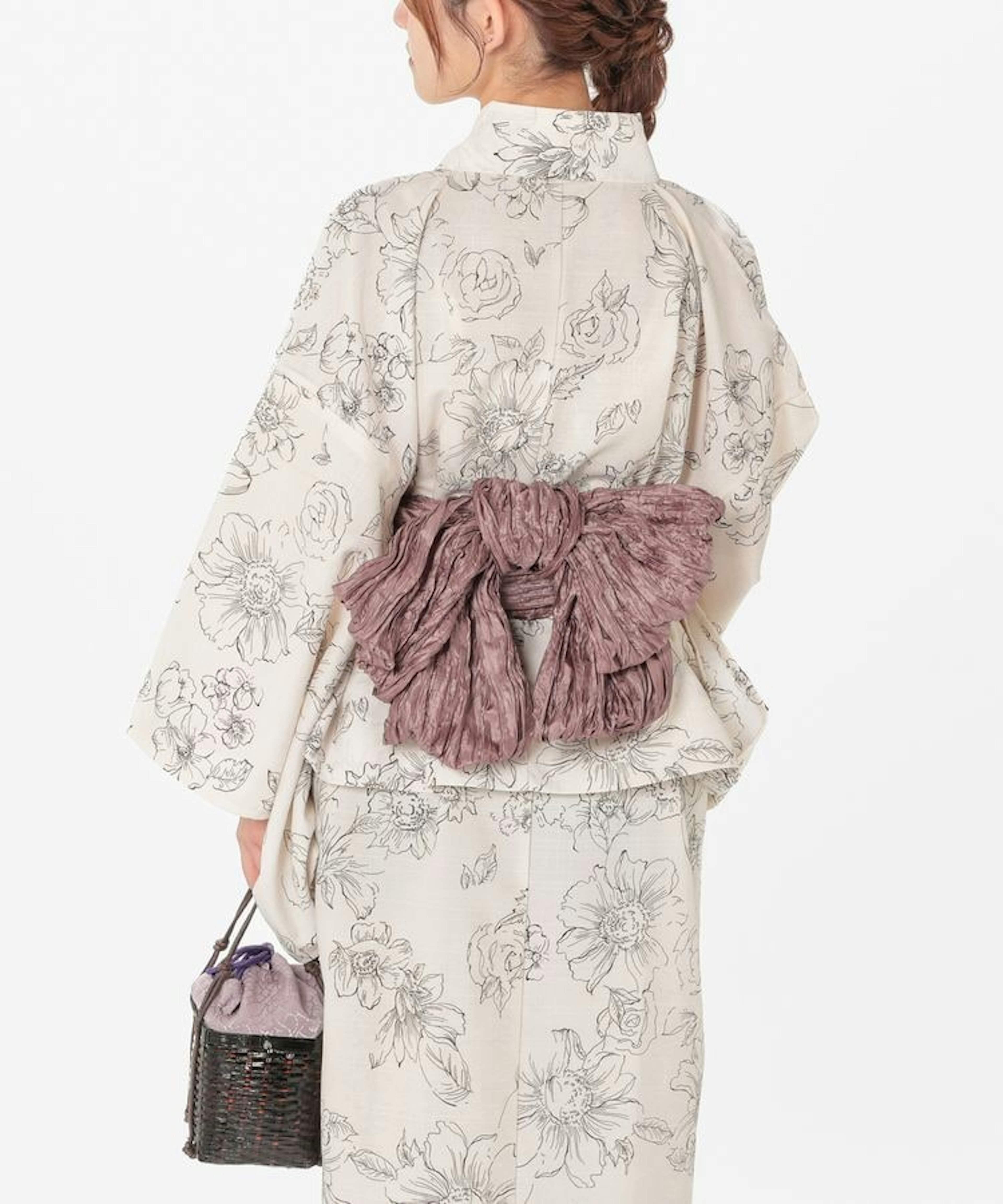 白地に花柄の浴衣を着た女性。背中には大きな紫の帯が結ばれ、手には籠バッグを持っている。