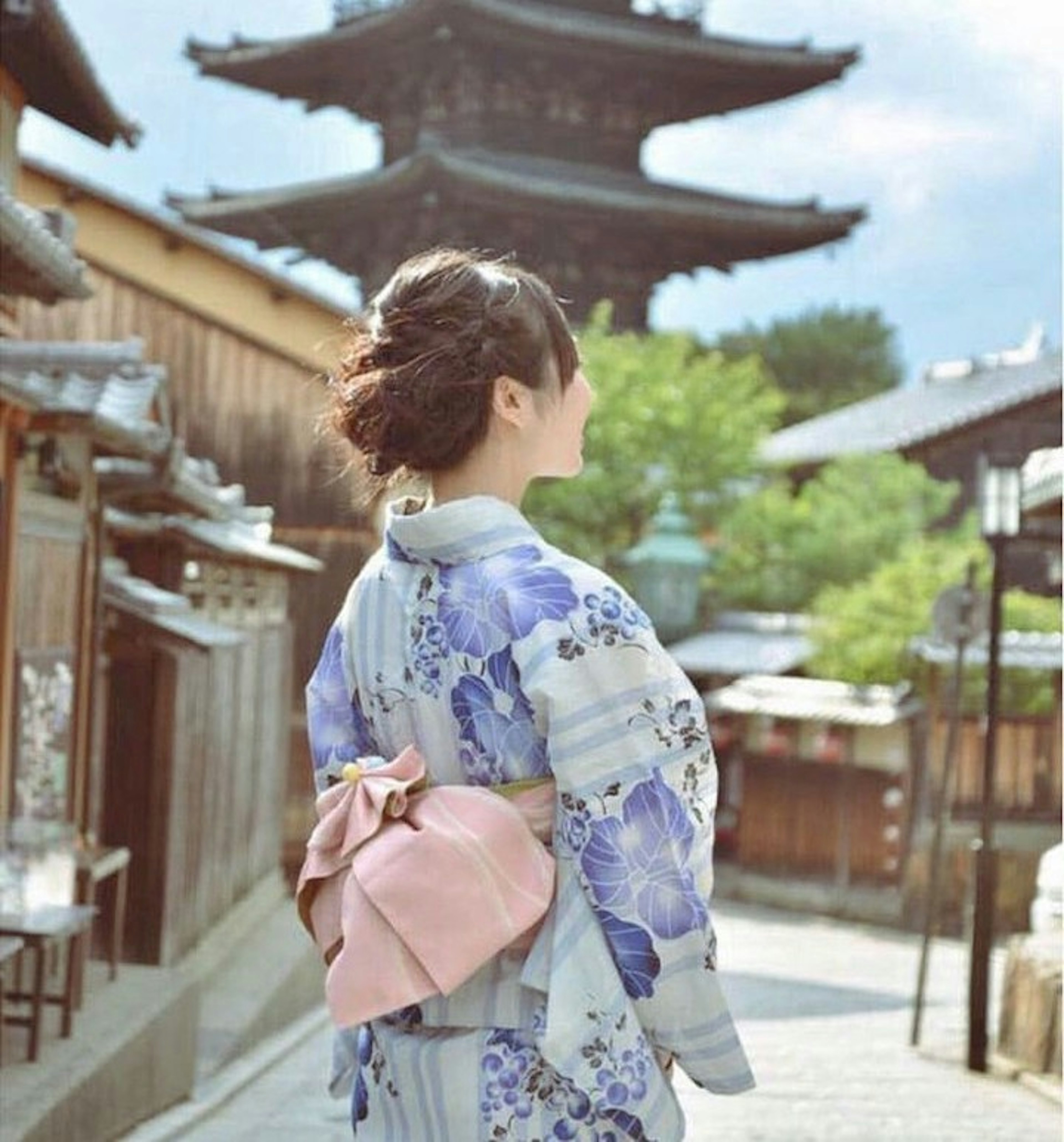 三重塔をバックに散策している浴衣姿の女性